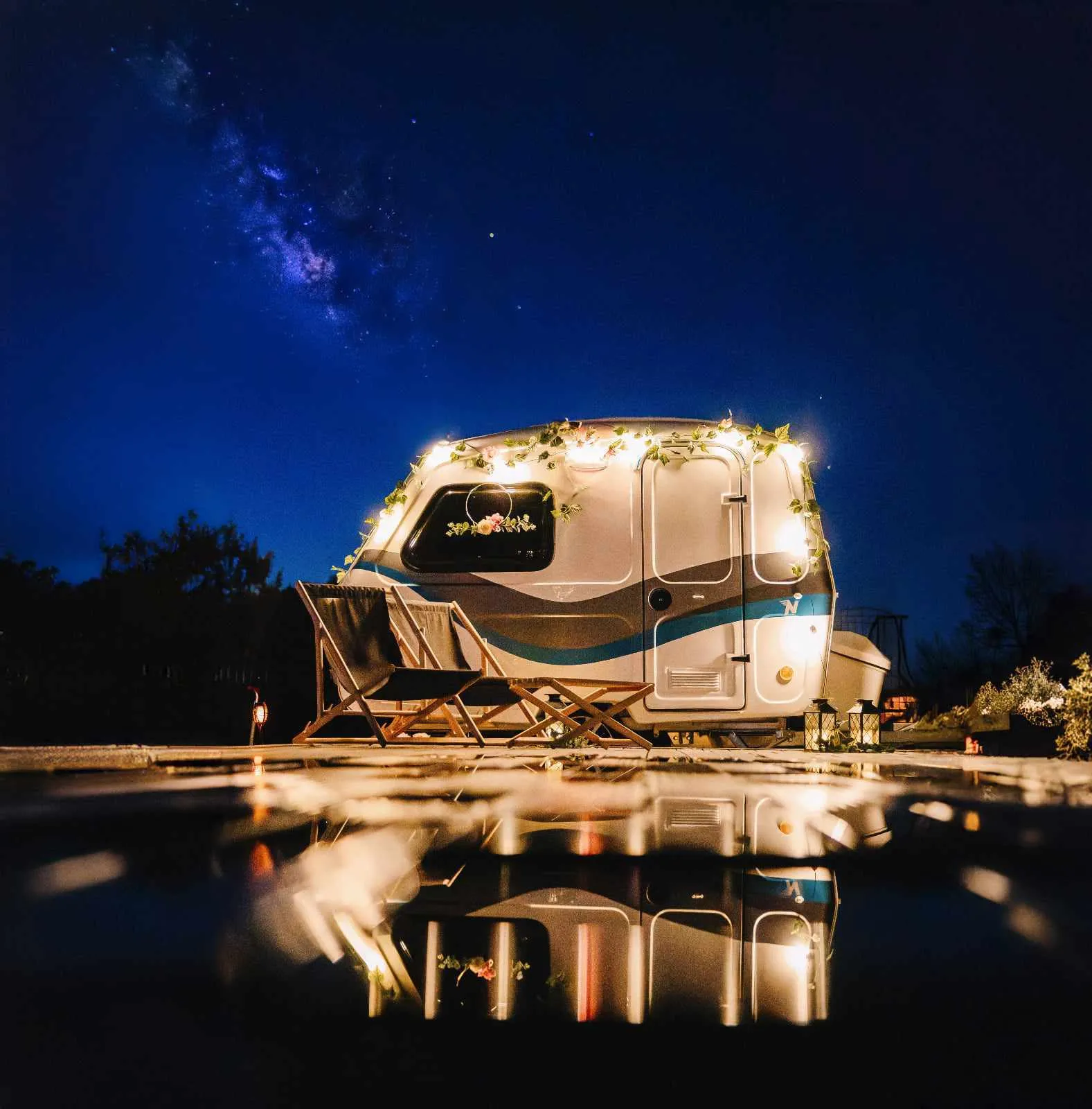 FotoPrzyczepa All-in nocą, pod rozgwieżdżonym niebem, oświetlona girlandą żarówek